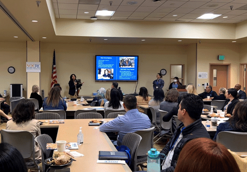 NOCRC Partners breakfast presentation with a room filled with people.